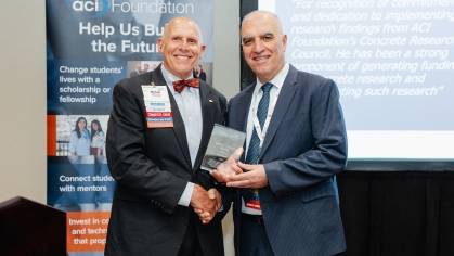 Male professor receives award from another male standing in front of an ACI Foundation banner.