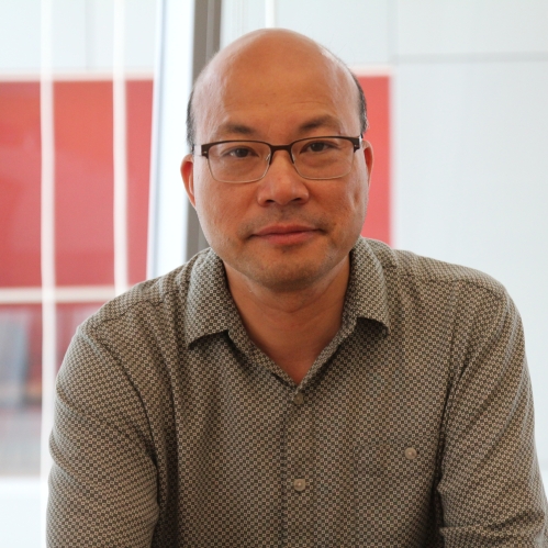 head shot of Asian man with eyeglasses and wearing a grey button down shirt