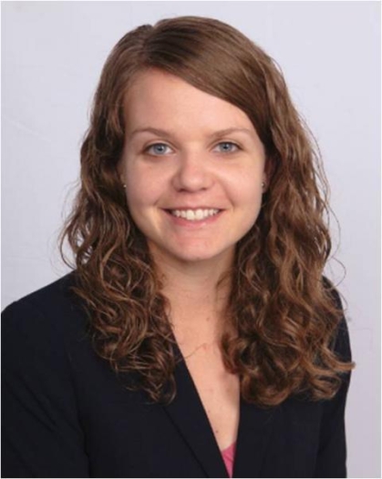 head shot of female with curly long brown hair wearing a black suit jacket 