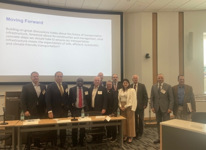 Group of men and women posing in front of large monitor