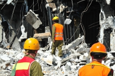 Photo of three engineers walking among rubble from and earthquake